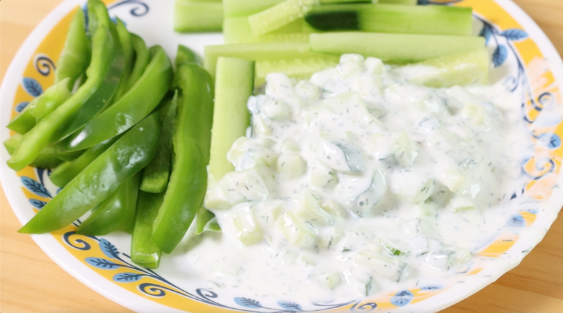 plate with cucumber dip served with cucumber sticks and fresh snap peas