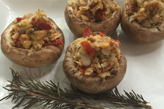 herb stuffed mushrooms on white plate with a sprig of rosemary