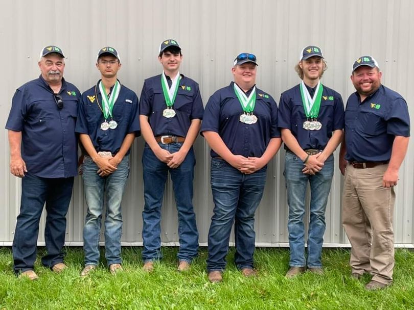 Six men dressed in navy blue shirts with the Flying WV and 4-H Clover pose with medals they won at the National 4-H Shooting Sports Championships.