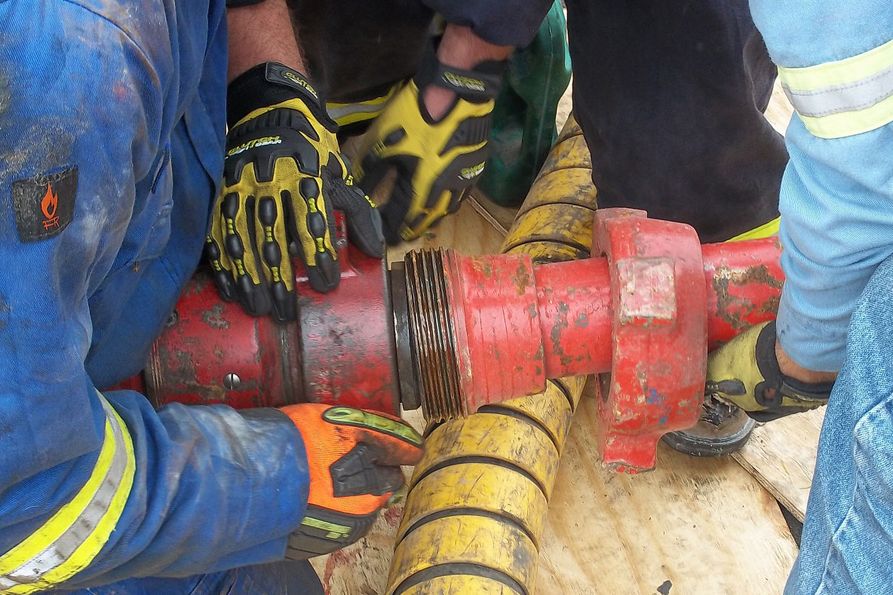 Hydraulic fracturing workers connect iron using their hands