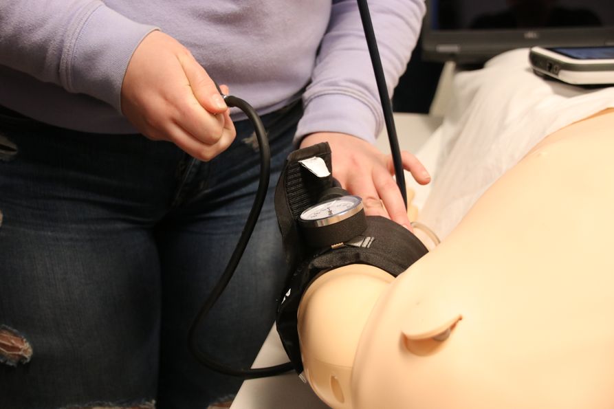 Student taking blood pressure on simulation mannequin.
