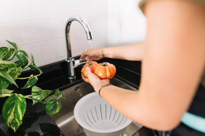 woman washing tomato at the sink