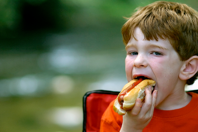 red haired boy eating a hot dog