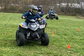 Youths wearing helmets while riding on ATVs.